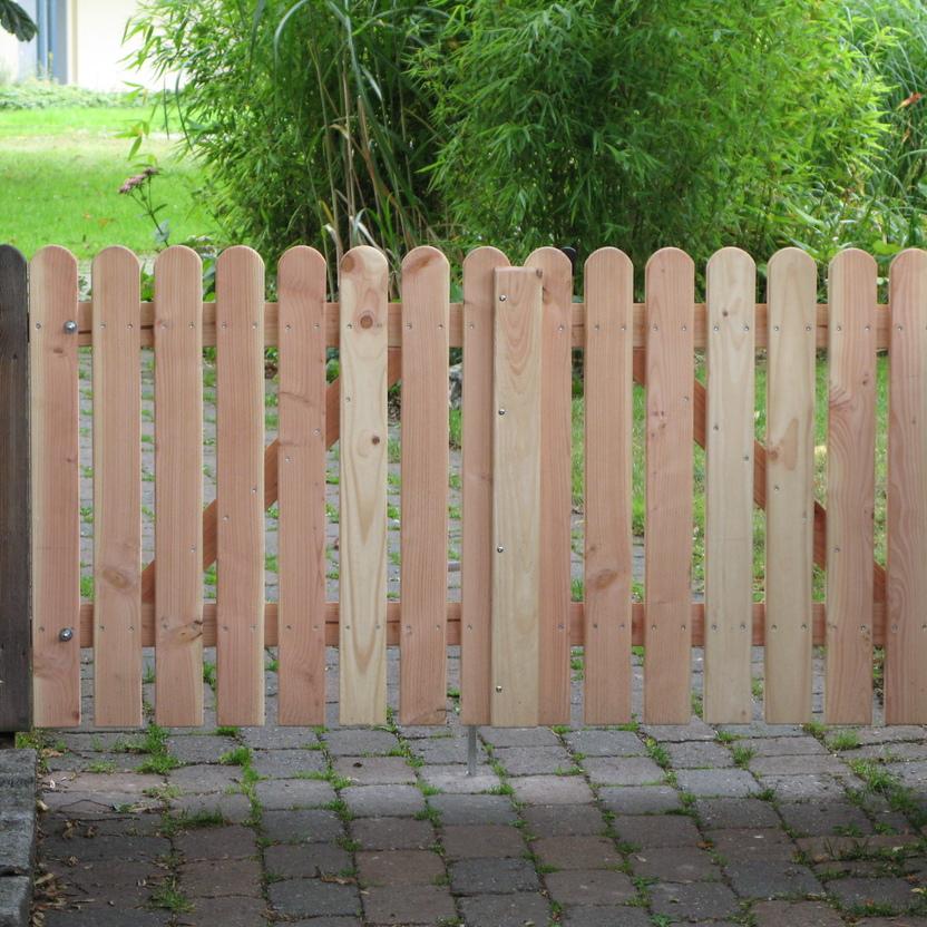 Holzgartentor in einem gepflasterten Eingang Ein neu installiertes Holzgartentor trennt einen gepflasterten Weg von einem grünen Garten. Ideale Lösung für stilvolle Gartentore.