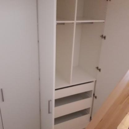 Maßgeschneiderter Einbauschrank in einer Ecke Ein großer, weißer Einbauschrank nach Maß, in einer Raumtiefe positioniert, bietet sowohl Regalfächer als auch Schubladen für optimierte Aufbewahrungslösungen.