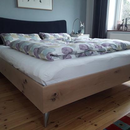 Stilvolles Schlafzimmer mit modernem Holzbett Modernes Holzbett mit klaren Linien und Metallbeinen, ausgestattet mit bunter Bettwäsche in einem gemütlichen Schlafzimmer mit Holzboden.