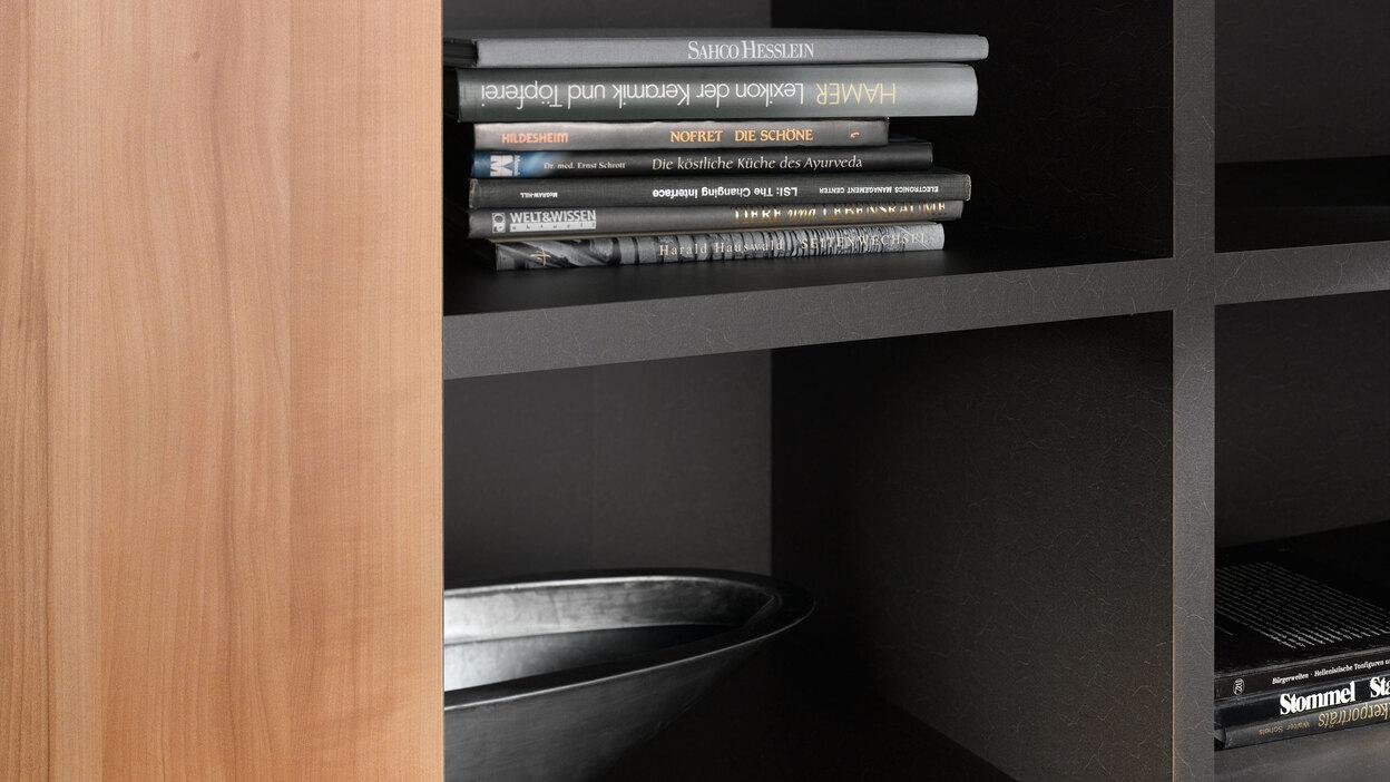 Detailaufnahme eines schwarz lackierten Regals mit Büchern und Schale in Kombination mit naturbelassenem Holz.