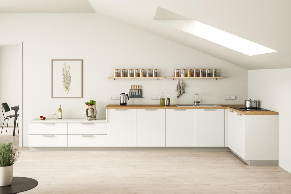 Luftige Küche nach Maß unter Dachschräge mit weißen Schränken, Holzarbeitsplatte und offenen Regalen, durchflutet von Tageslicht.