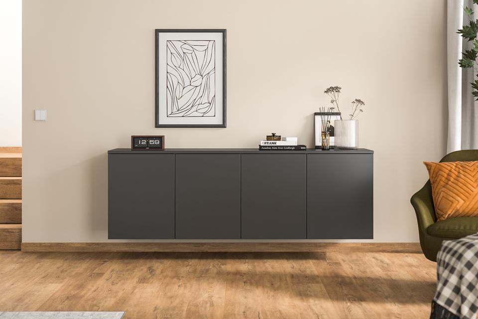 Ein maßgeschneidertes Hängeboard in Anthrazit ergänzt den Wohnraum, stilvoll unter einem abstrakten Gemälde und neben einer grünen Samtsessel platziert.